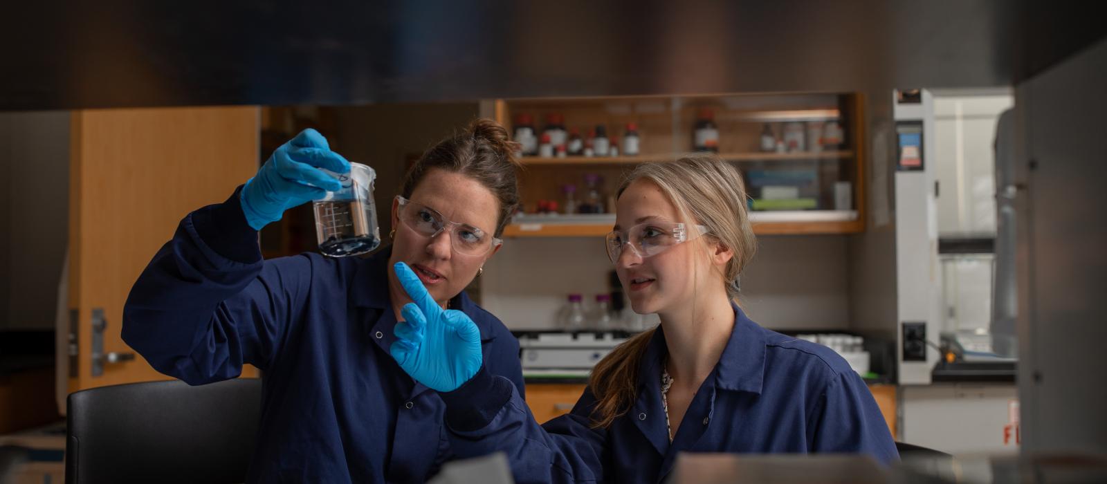 Researchers looking at a beaker of liquid