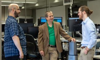 Researchers talk amongs the equipment in a lab.